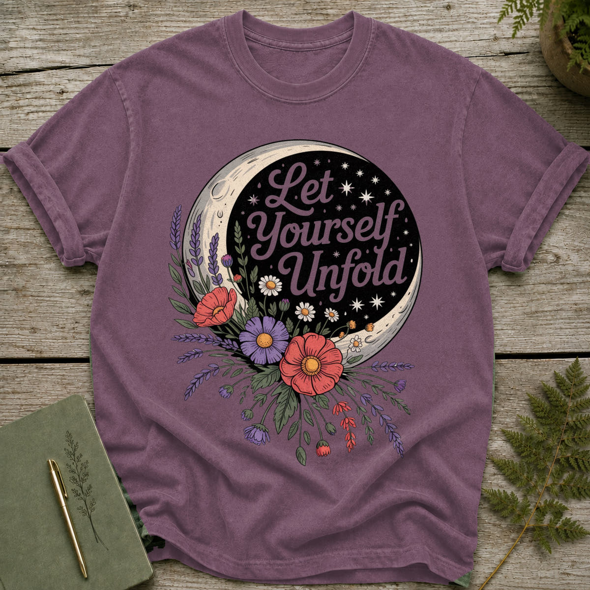 Purple t-shirt with "Let Yourself Unfold" text and moon surrounded by flowers.