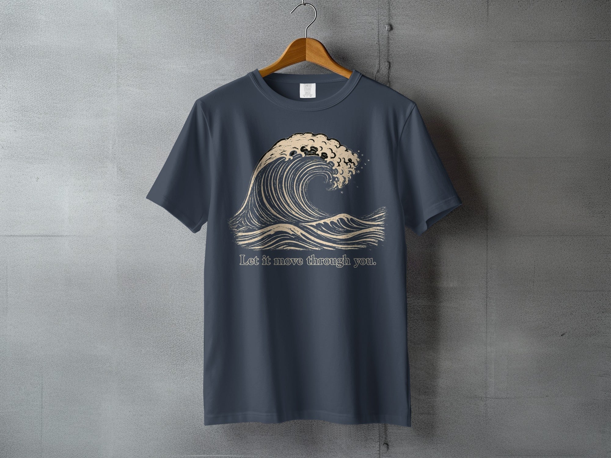 Dark blue t-shirt with a beige wave graphic and text "Let it move through you."