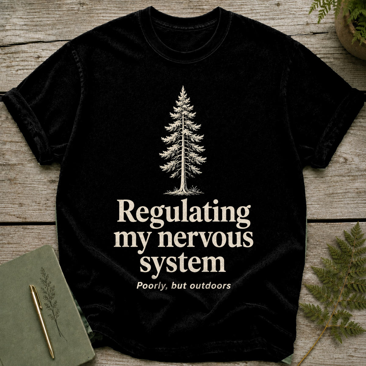 Black t-shirt with a pine tree and text: "Regulating my nervous system, Poorly, but outdoors."