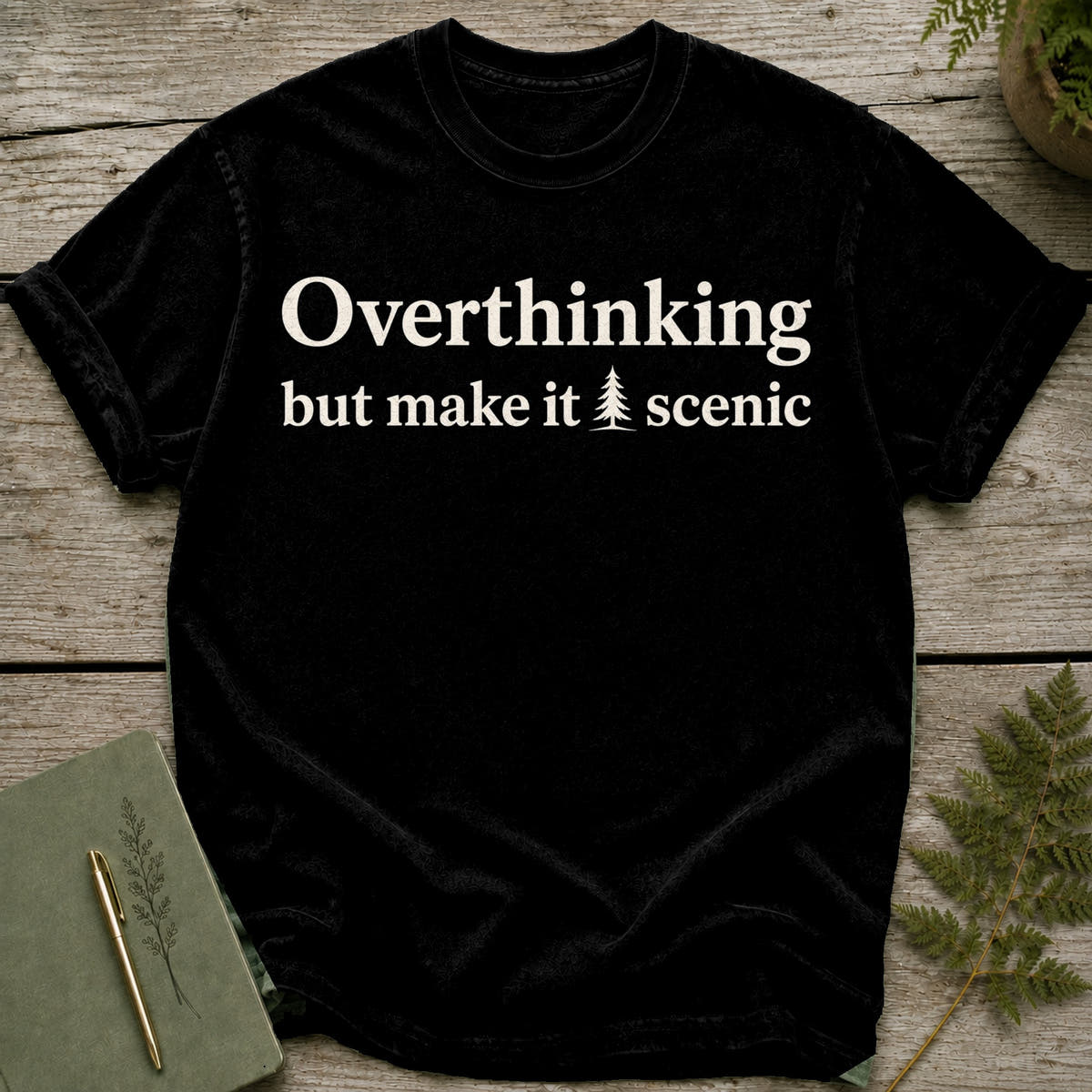 Black t-shirt with white text "Overthinking but make it scenic" and a small tree graphic.