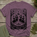 T-shirt with witches dancing around a fire with a black cat overhead.