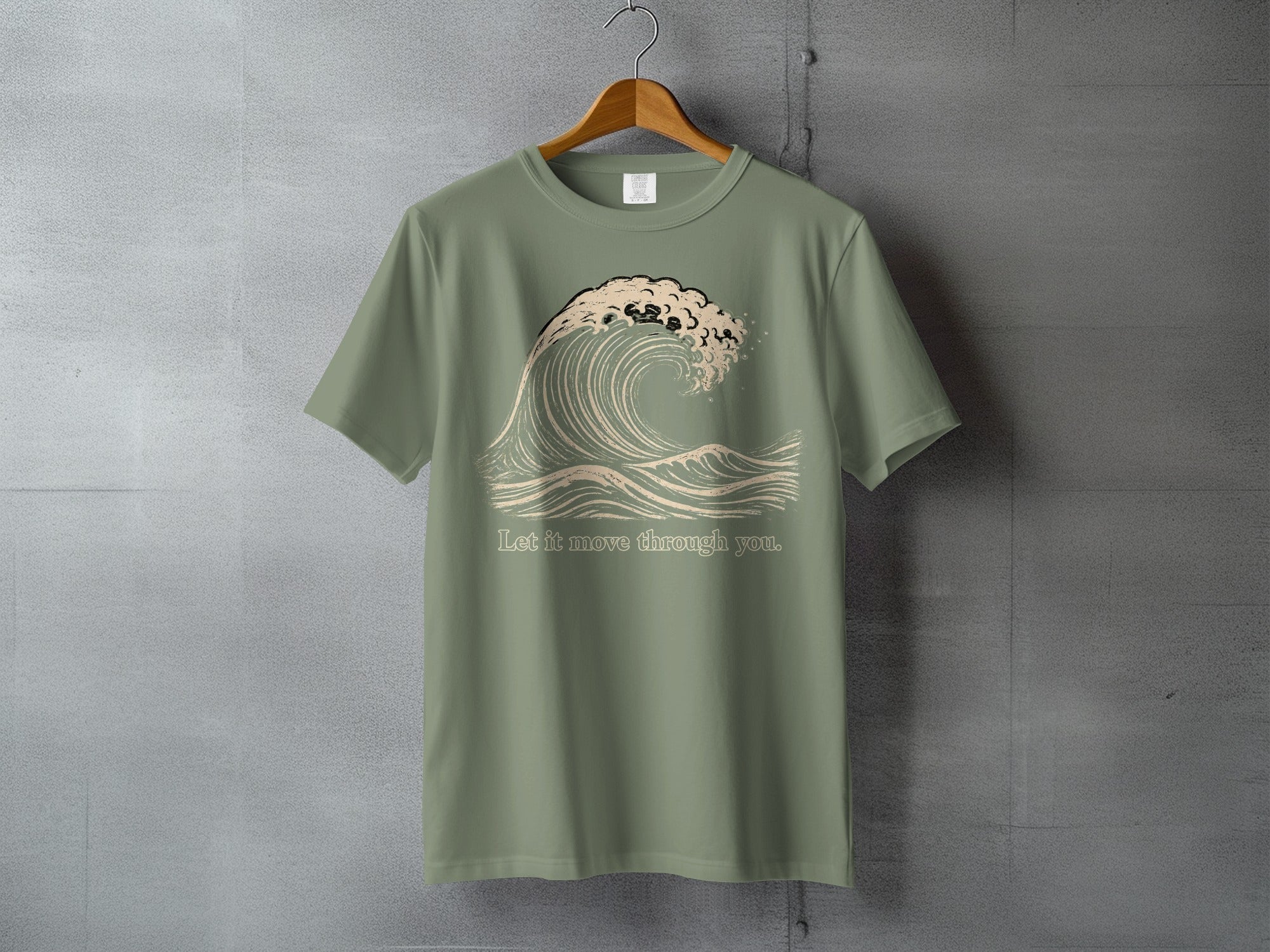 Olive green t-shirt with a wave graphic and text reading "Let it move through you."