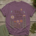 Purple t-shirt with flowers, bees, butterflies, and text "Today is a good day to bloom where you are".