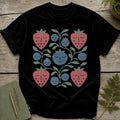 Black t-shirt with a square folk art print of strawberries and blueberries with faces.