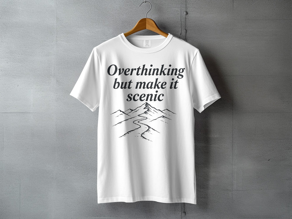 White t-shirt with black text "Overthinking but make it scenic" and mountain graphic.