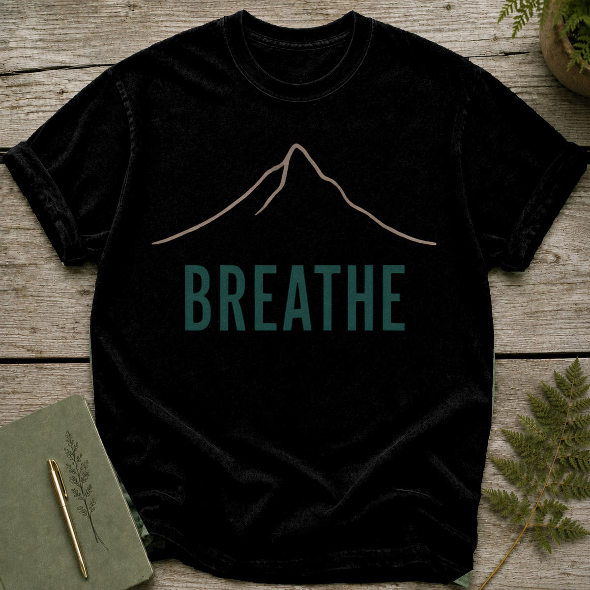 Black t-shirt with a minimalist mountain graphic and the word "BREATHE" printed in teal.