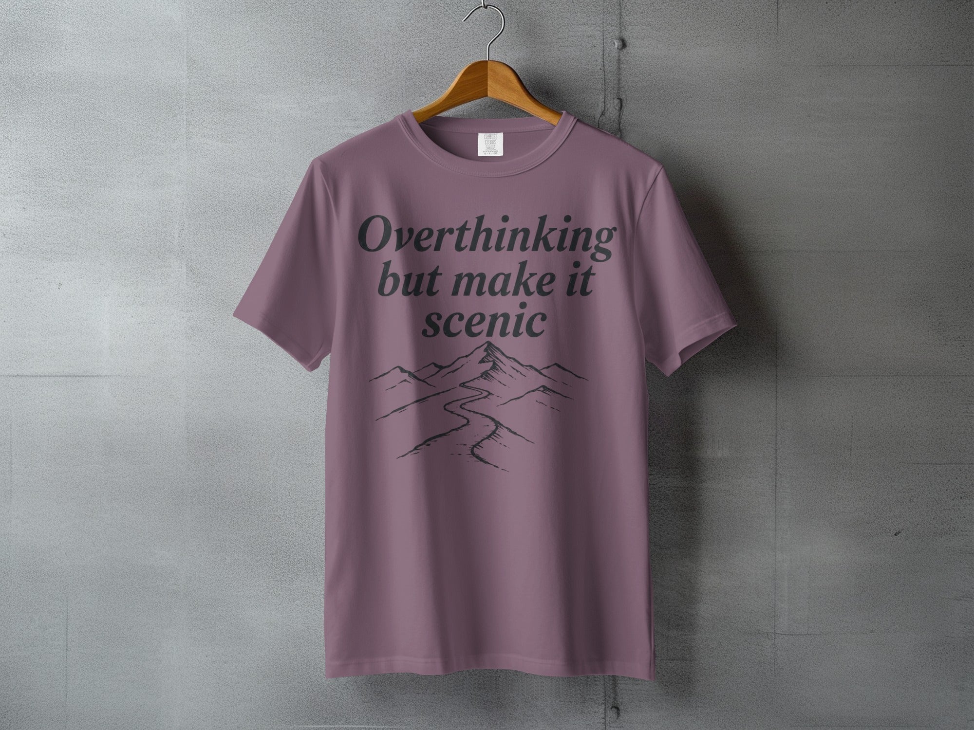 Purple t-shirt with "Overthinking but make it scenic" text and mountain graphic.