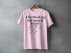 Pink t-shirt with "Overthinking but make it scenic" text and mountain path design.