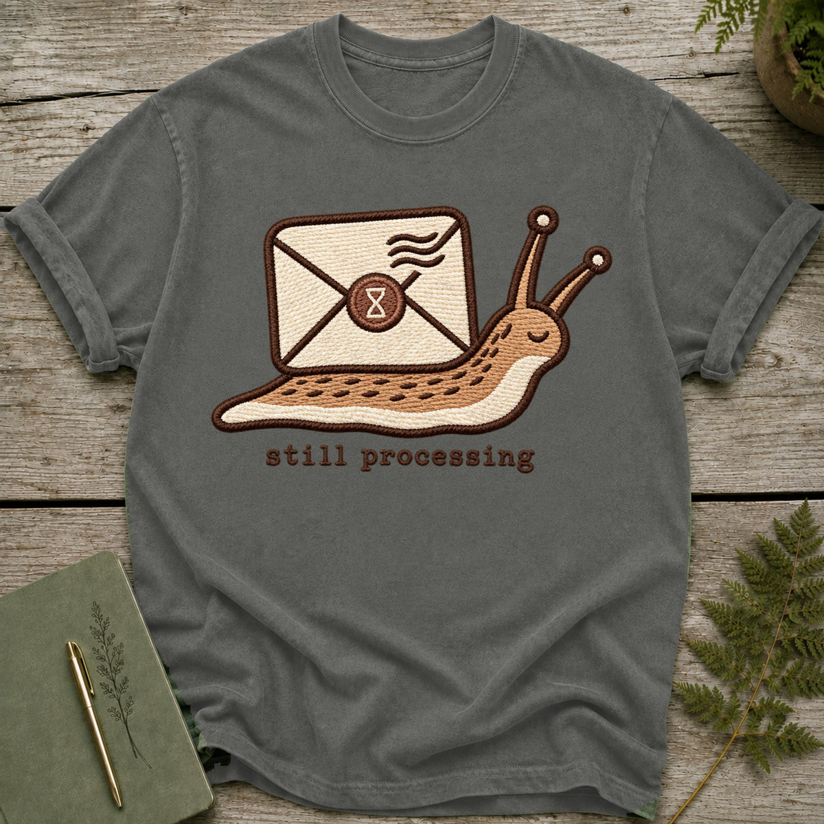 T-shirt with embroidered slug carrying an envelope with "still processing" text.